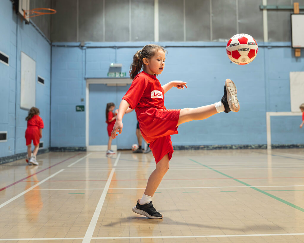 Little kickers kid kicking a soccer ball inside